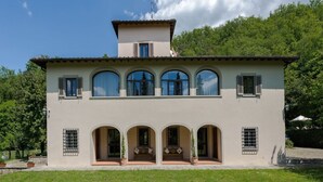 A two-story house with a flat roof, large arched windows, and a front porch with potted plants. - Belvilla by OYO Villa Arnia (Reggello)