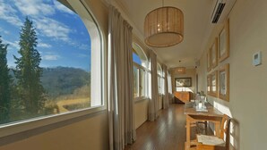 A corridor with wooden flooring, large windows, and a view of a forest. - Belvilla by OYO Villa Arnia (Reggello)