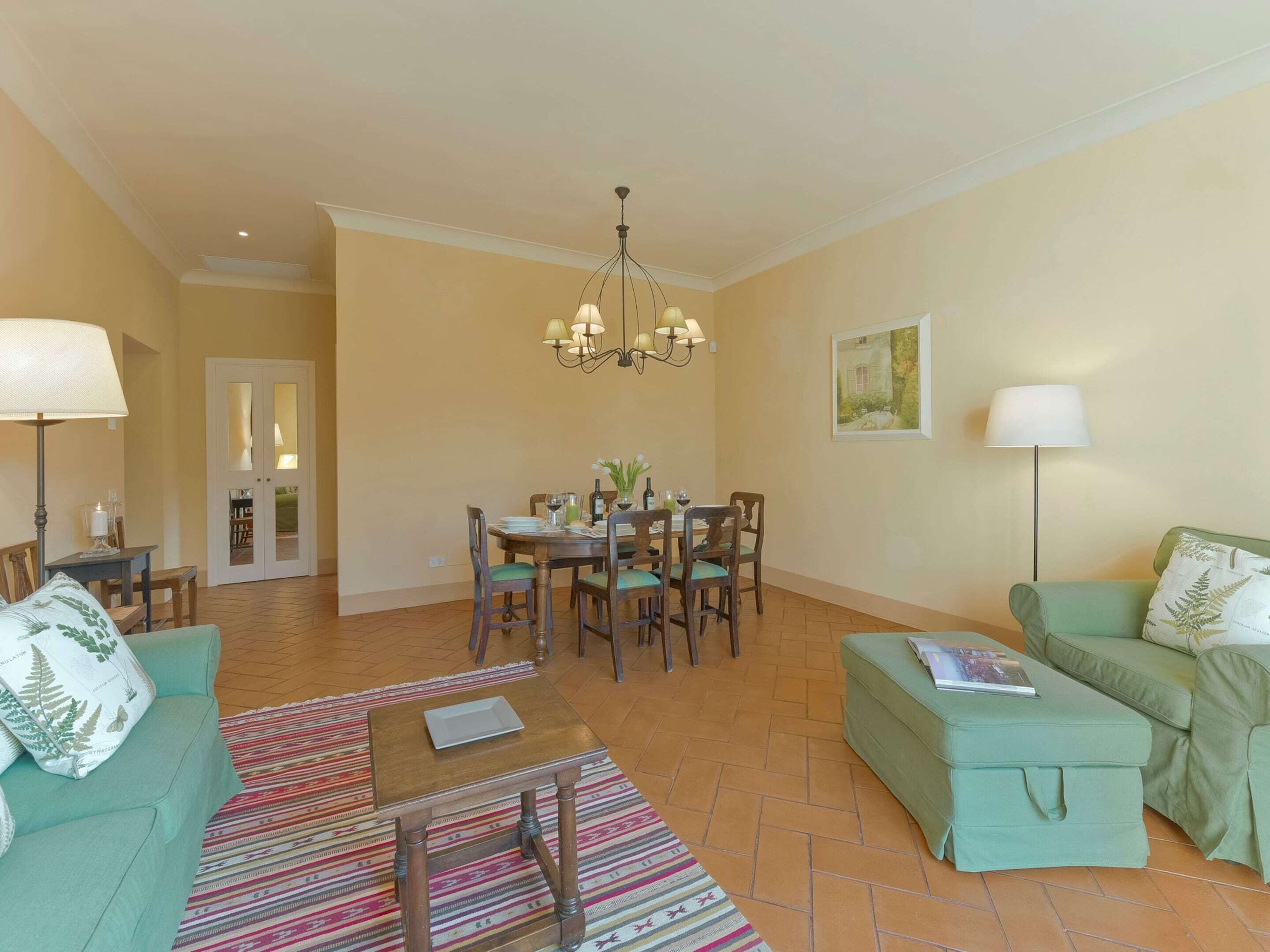 Un soggiorno con zona pranzo, un divano, un tavolino, una lampada e un lampadario.