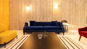 A modern living room with a dark blue sofa, a yellow armchair, and a red chair. A black coffee table with a glass pitcher and candles is in the center. - The Victoria Park Sanctuary - Stunning 2bdr Flat (London)