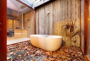 Een moderne badkamer met een vrijstaand bad, houten wanden en een douchecabine van glas.