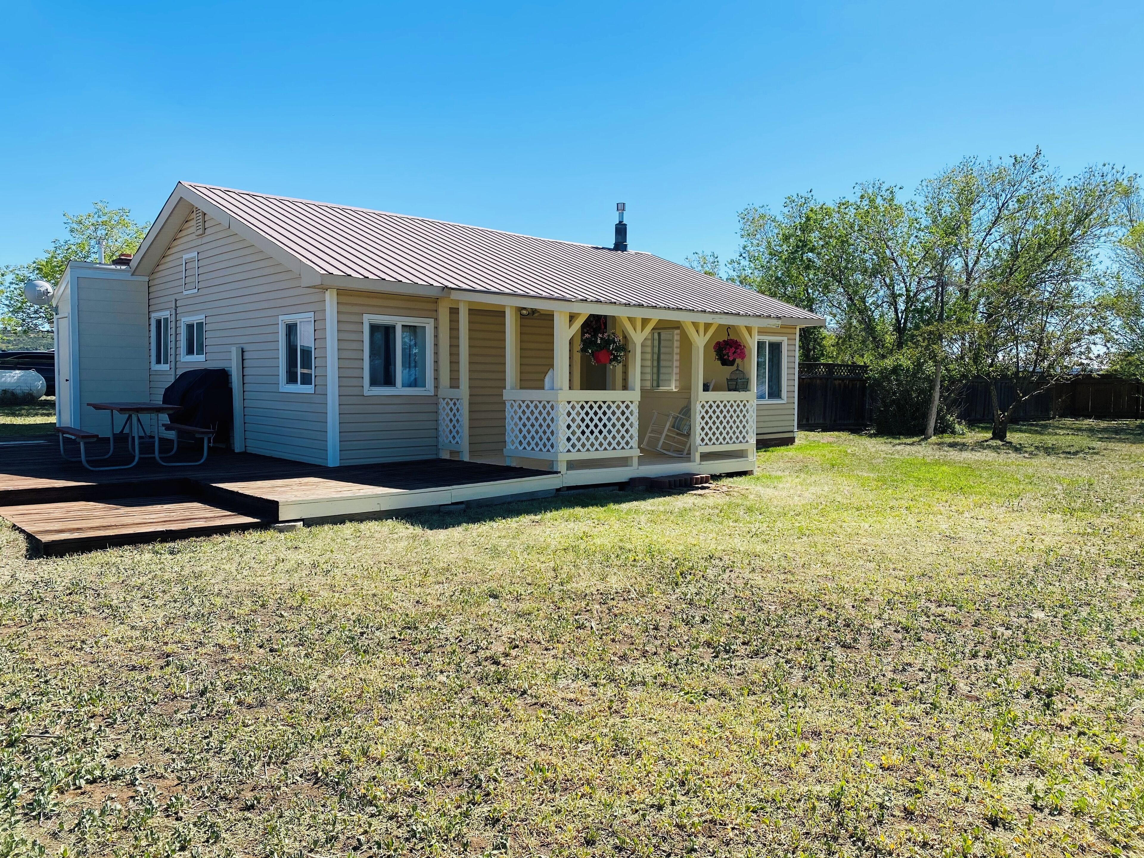 A single-story house with a porch, a picnic table, and a barbecue grill.