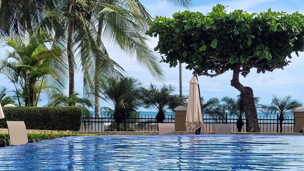 A swimming pool with clear blue water, surrounded by palm trees and a beach view. - Stay on the Beach at Acqua Condo (Puntarenas Province)
