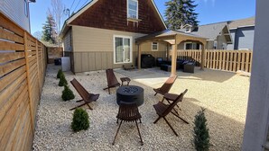 Un jardin avec un patio couvert, un espace salon extérieur et un barbecue.