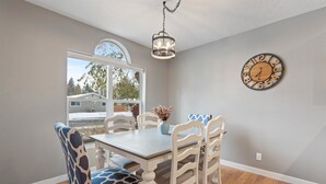 Un coin repas avec une table et des chaises en bois, un lustre et une horloge murale.