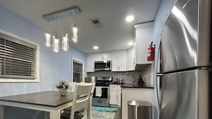 A modern kitchen with white cabinets, stainless steel appliances, and pendant lighting.