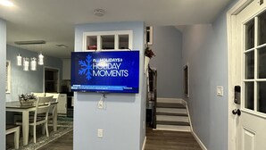A living room with a large blue wall, a patterned rug, a flat-screen TV, and a staircase leading to another room.