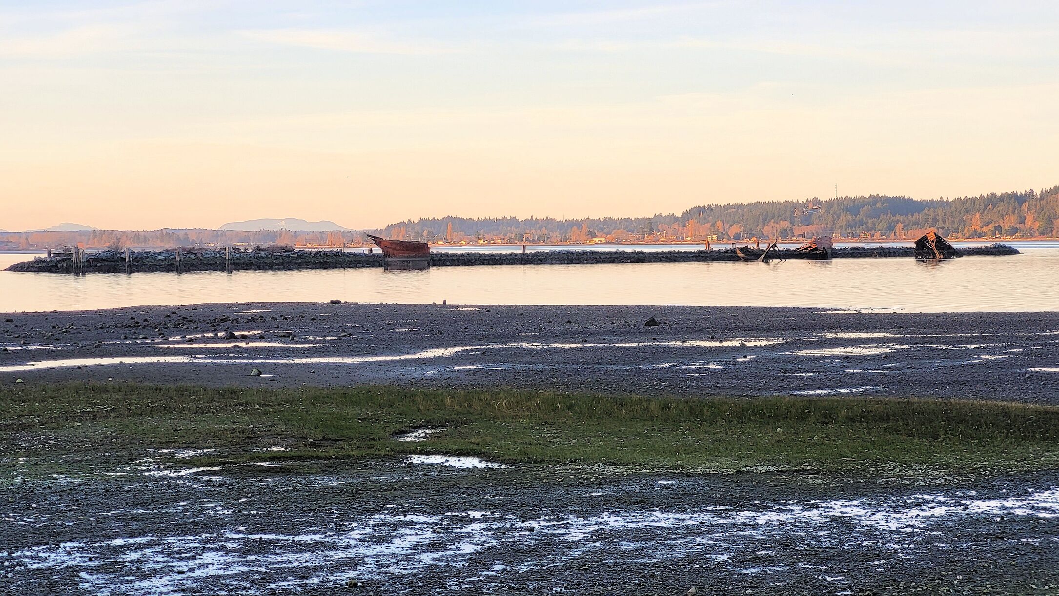 A rocky shoreline with a boat stranded on a small island.
