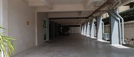 A covered parking area with concrete flooring and structural beams.