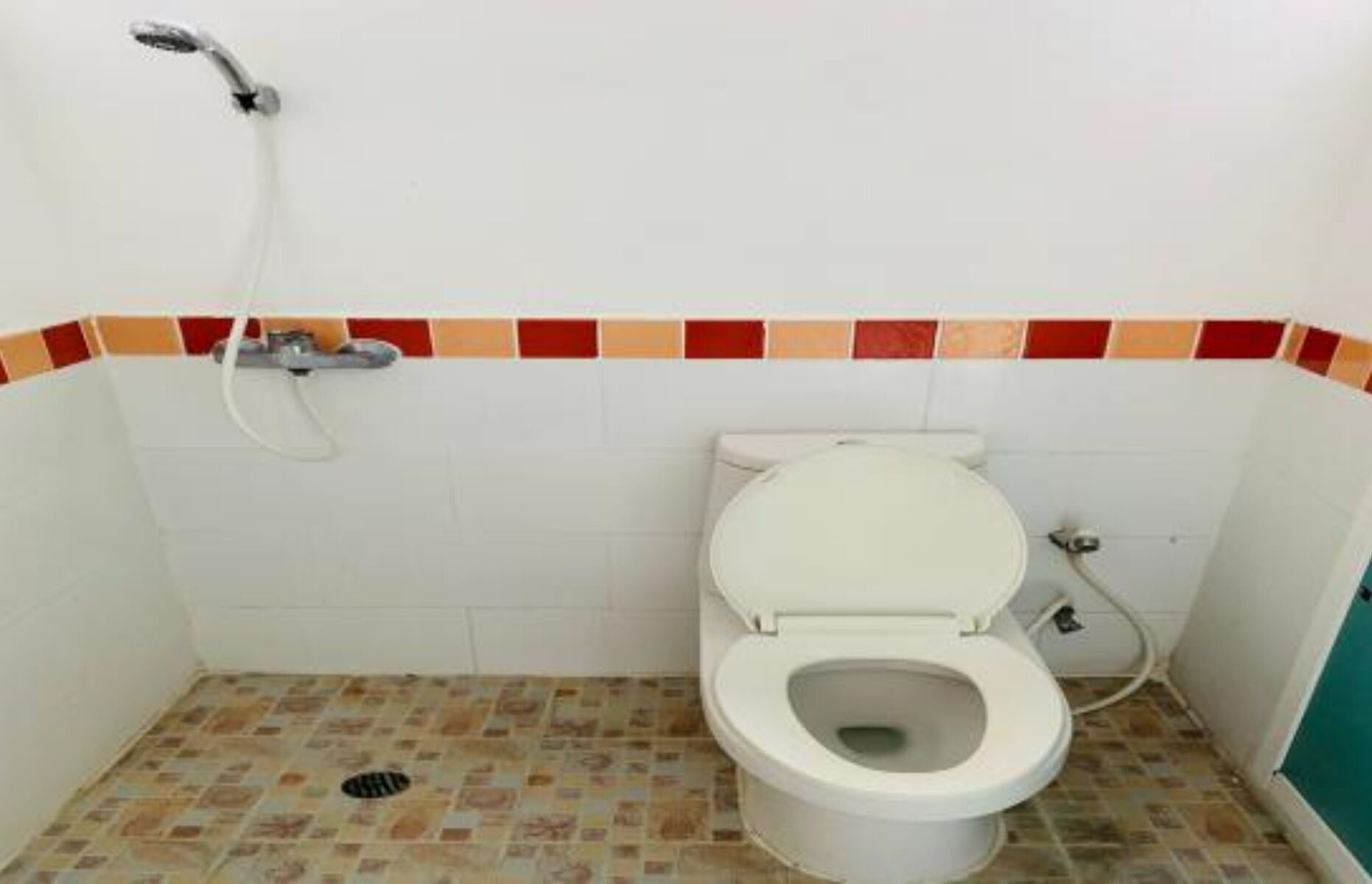 A small, tiled bathroom with a toilet, a shower, and a tiled floor.