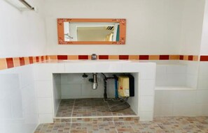A bathroom with a tiled floor, a sink with a mirror above it, and a towel rack. - Grandview Place (Bangkok)