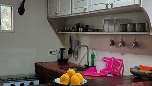 A kitchen with white cabinets, a sink, and a stove. There are lemons on the counter and a pink dish rack.