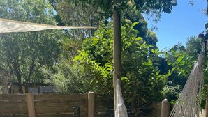 A patio with a hammock, a cushioned seating area, and a wooden fence.