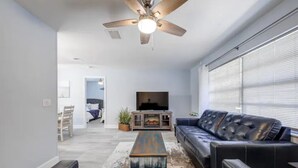A modern living room with a black leather sofa, a wooden coffee table, and a ceiling fan. - 🏝️10 MINS TO BEACH # HEATED POOL/SPA # SLEEP FOR 12@ KIDS FRIENDLY (Melbourne)