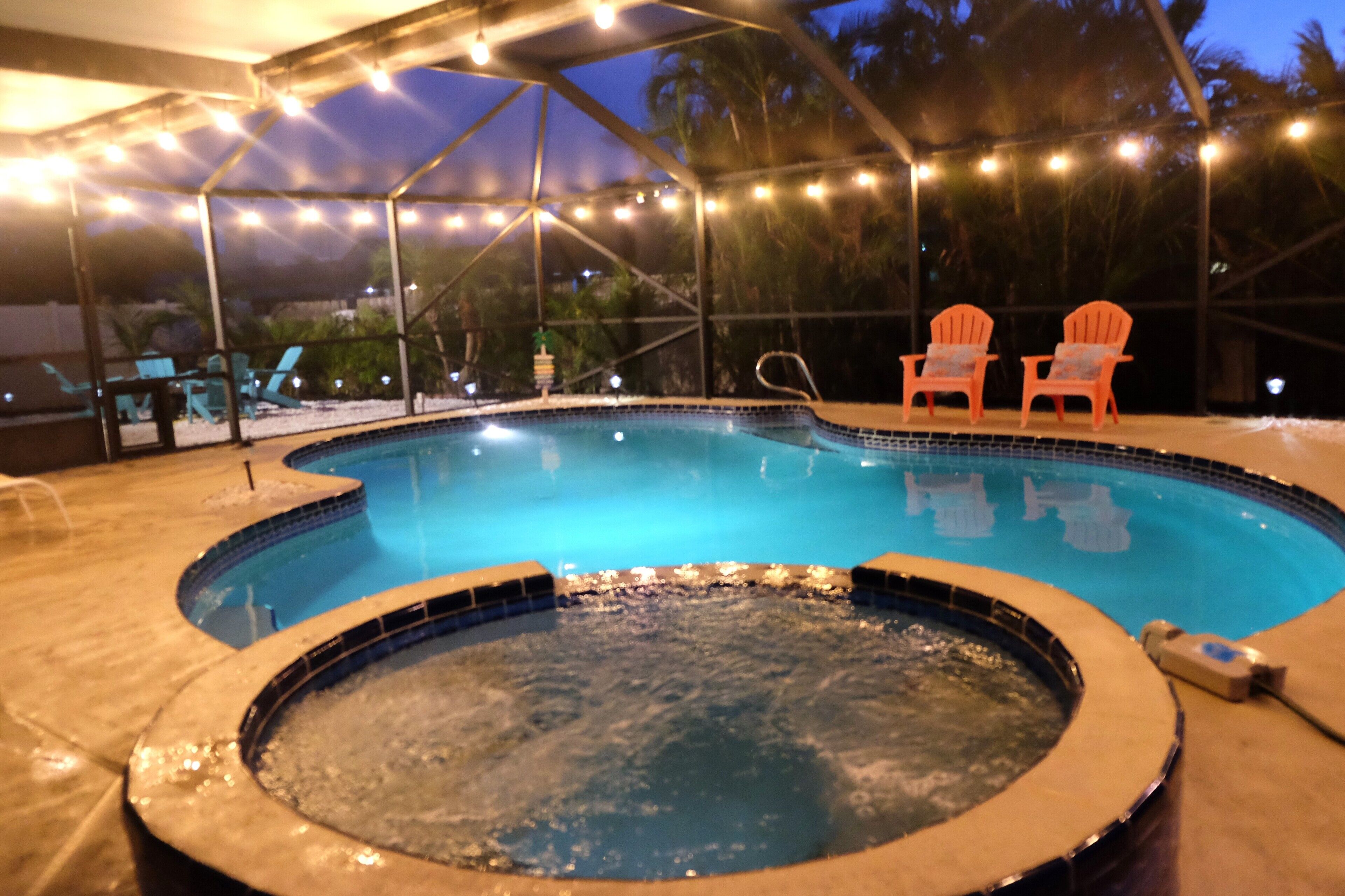 A hot tub and a pool under a covered area with string lights.