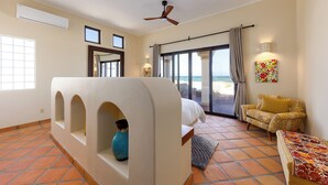 A bedroom with a bed, a sofa, a ceiling fan, a window, and a view of the beach. - Beachfront Hacienda on the Sea of Cortez with pool near Four Seasons Resort (La Ribera)