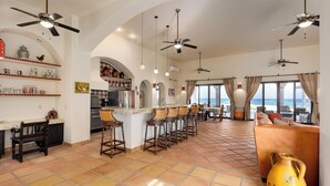 A spacious kitchen with a bar area, a dining area with a view, and a living room with a large sofa and a decorative vase. - Beachfront Hacienda on the Sea of Cortez with pool near Four Seasons Resort (La Ribera)