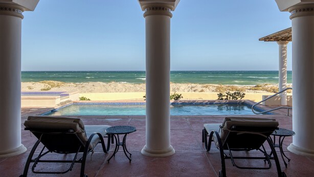 A poolside area with two lounge chairs and a small table, overlooking a beach and ocean. - Beachfront Hacienda on the Sea of Cortez with pool near Four Seasons Resort (La Ribera)