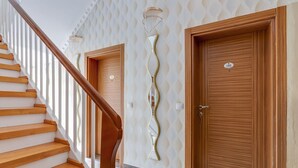 A staircase with wooden steps and a wooden handrail leading to a landing. There are two doors with a decorative wall design and a light fixture above them. - Cozy Corner in Oberhausen (Oberhausen)