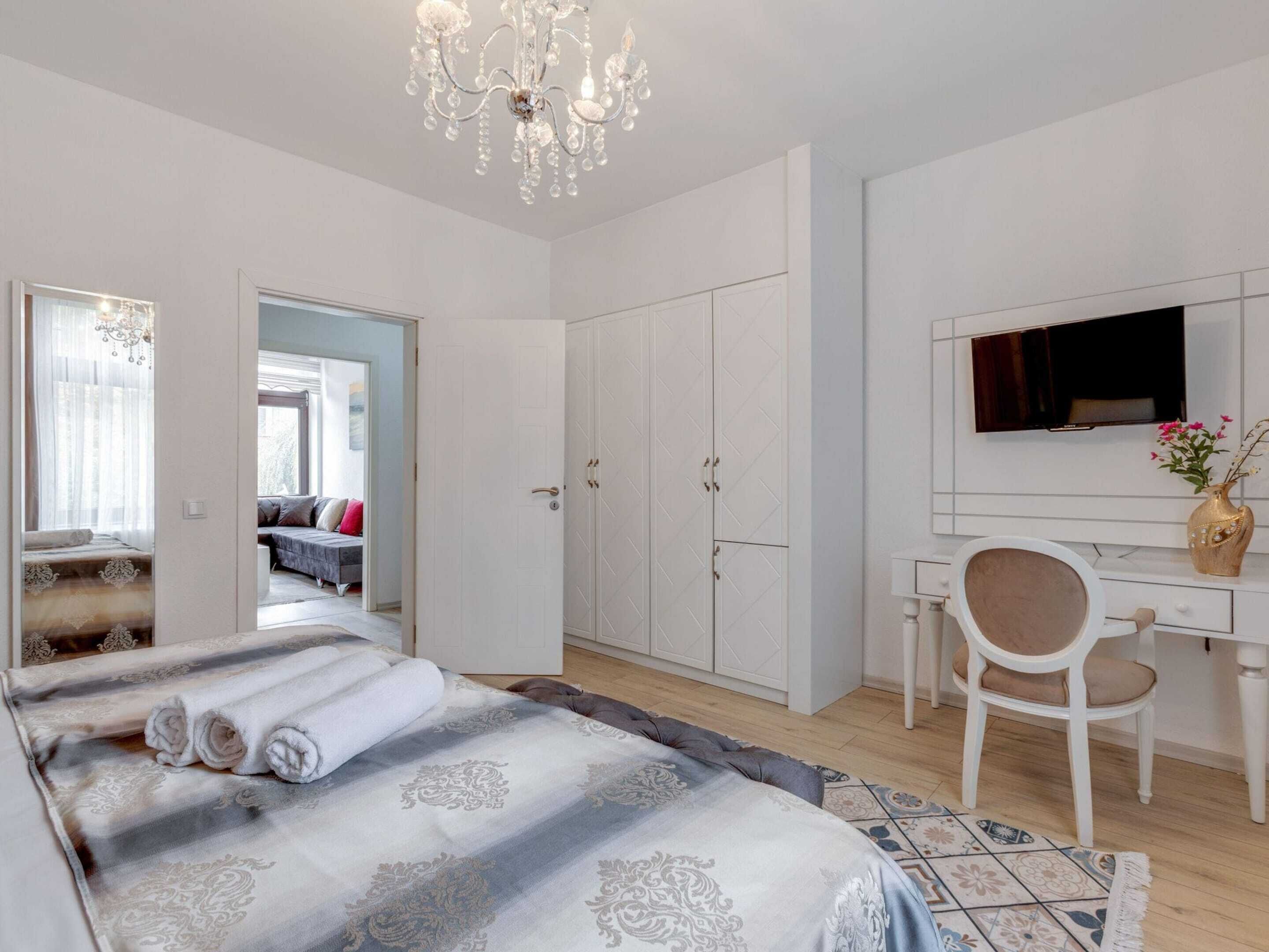 Une chambre moderne avec un grand lit, un bureau, une chaise et un téléviseur.