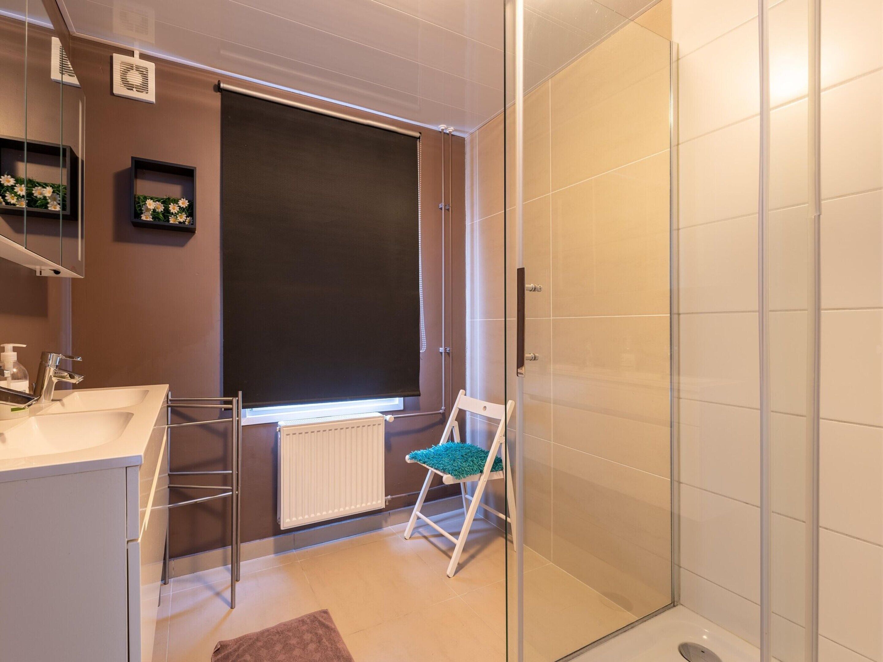 A modern bathroom with a white sink, mirror, and a glass shower enclosure.