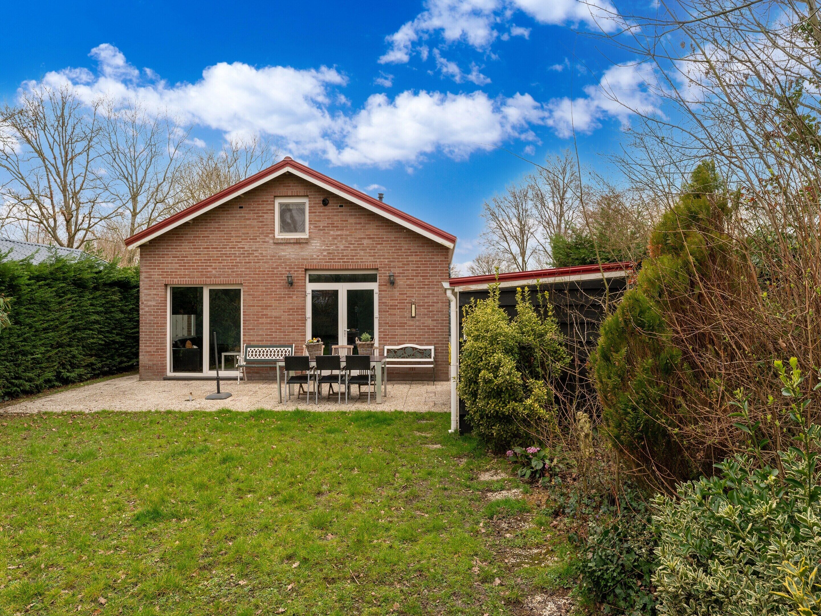 A brick house with a patio, a covered area, and a well-maintained lawn.