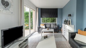 A modern living room with a flat-screen TV, a sofa, a coffee table, and a cabinet. - Holiday Home in Zeeland Near Lake (Baarland)