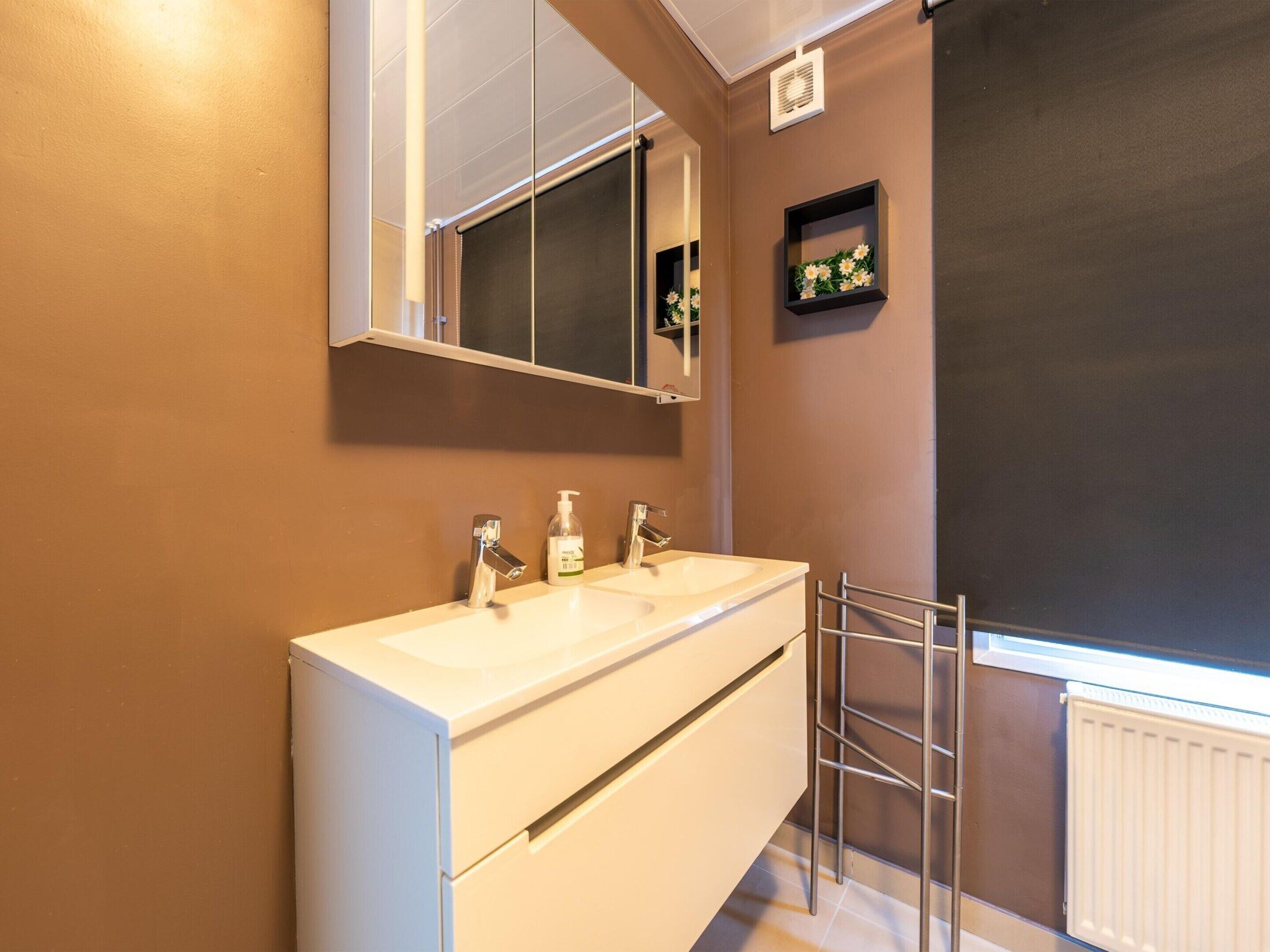 Een badkamer met twee wasbakken, een spiegel, een handdoekrek en een radiator.