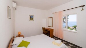 A bedroom with a bed, a desk, a chair, a window with a view, and a curtain. - Holiday Home Blue Vineyard- Three Bedroom House With Terrace and Sea View (Orebic)