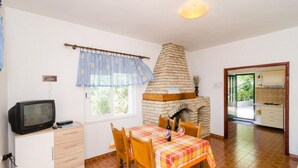 A dining area with a brick fireplace, a television on a cabinet, and a table set for two. - Holiday Home Blue Vineyard- Three Bedroom House With Terrace and Sea View (Orebic)