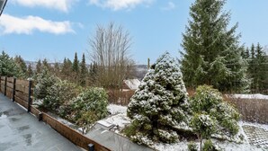 Paisaje nevado con valla de madera, árboles de hoja perenne y cielo despejado.