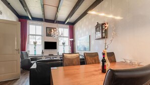 A modern living room with a wooden dining table, leather chairs, a flat-screen TV, and a chandelier. - Lovely Holiday Home From 1761 With Contemporary Comfort (Bad Nieuweschans)