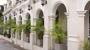 A row of white buildings with arched windows and planters with green plants. - Pran at Kumuang Boutique House (Chiang Mai)