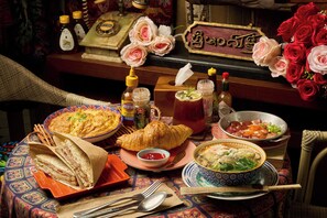 Una mesa servida con diversos platos, entre ellos un croissant, sopa y un bol de comida, junto con salsas y una botella.
