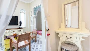 A bedroom with a wooden bed, a white vanity with a mirror, a wooden chair, and a yellow dresser.