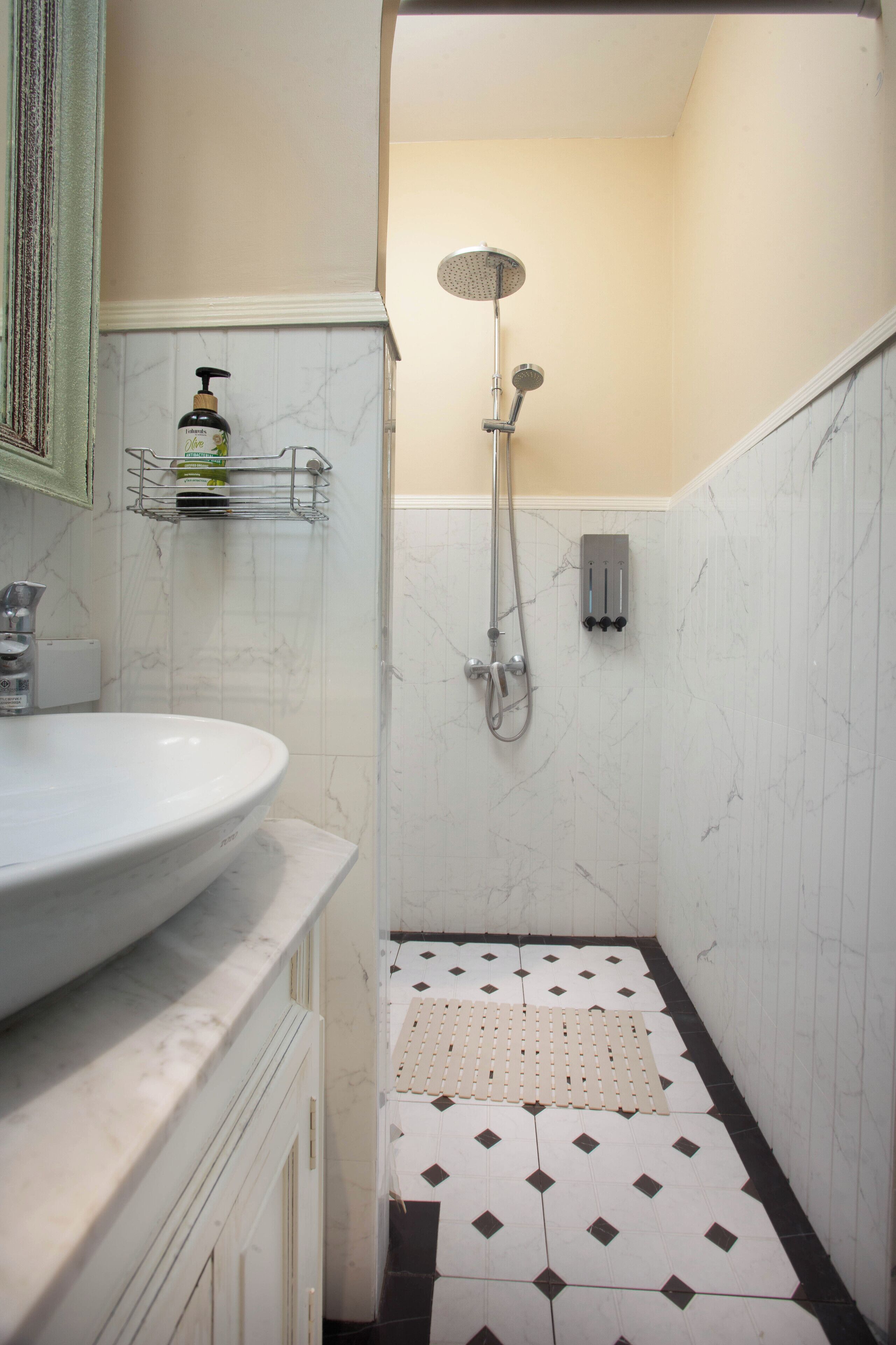 Un baño con lavamanos, ducha y piso de baldosas.