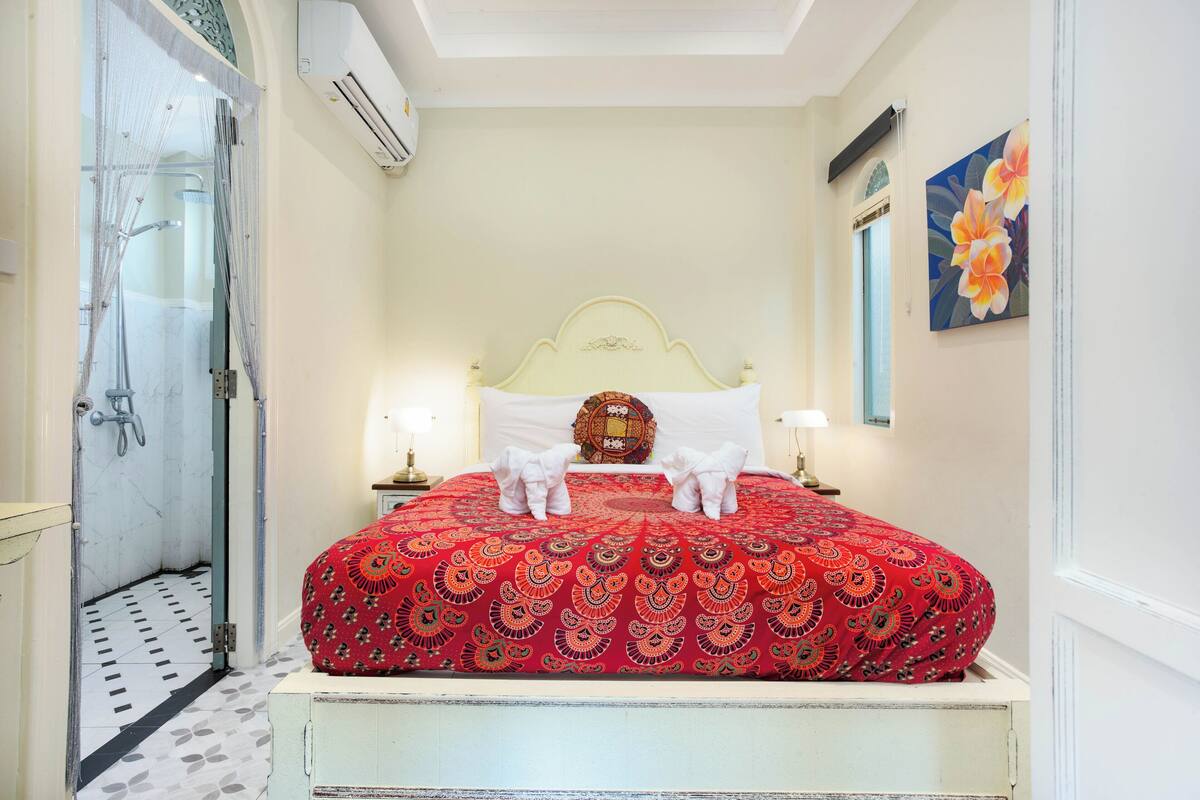 A hotel room with a bed, a shower, and a painting on the wall.
