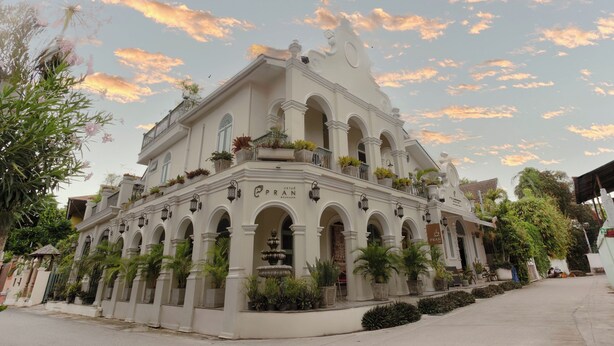 A historic building with multiple arches and balconies, surrounded by lush greenery. - Pran at Kumuang Boutique House (Chiang Mai)