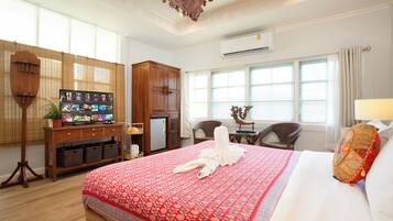 Habitación de hotel con una cama grande, un escritorio de madera con una computadora, una mesita con una silla y una ventana con cortinas.