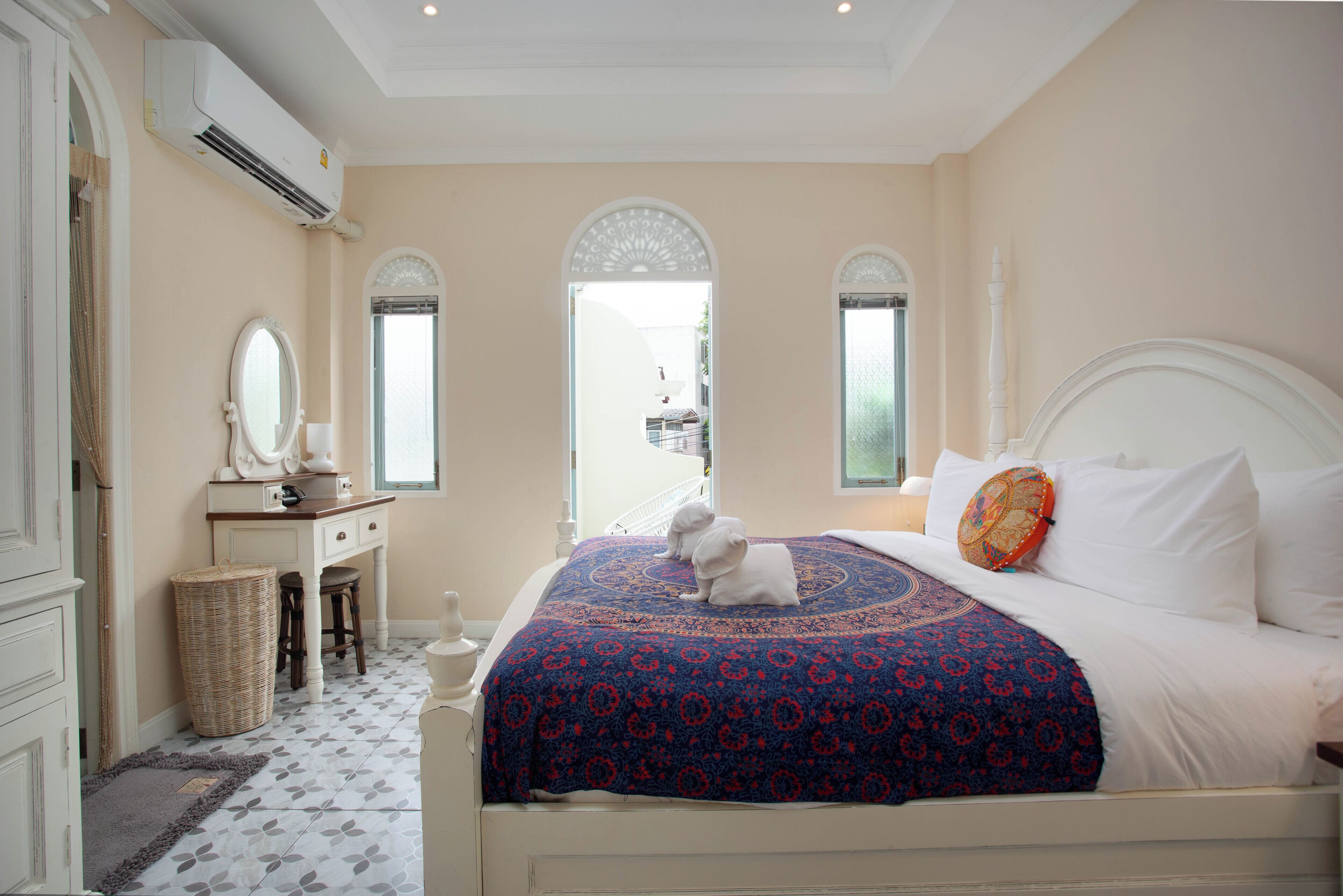 A bedroom with a bed, a dresser, a mirror, and a window.