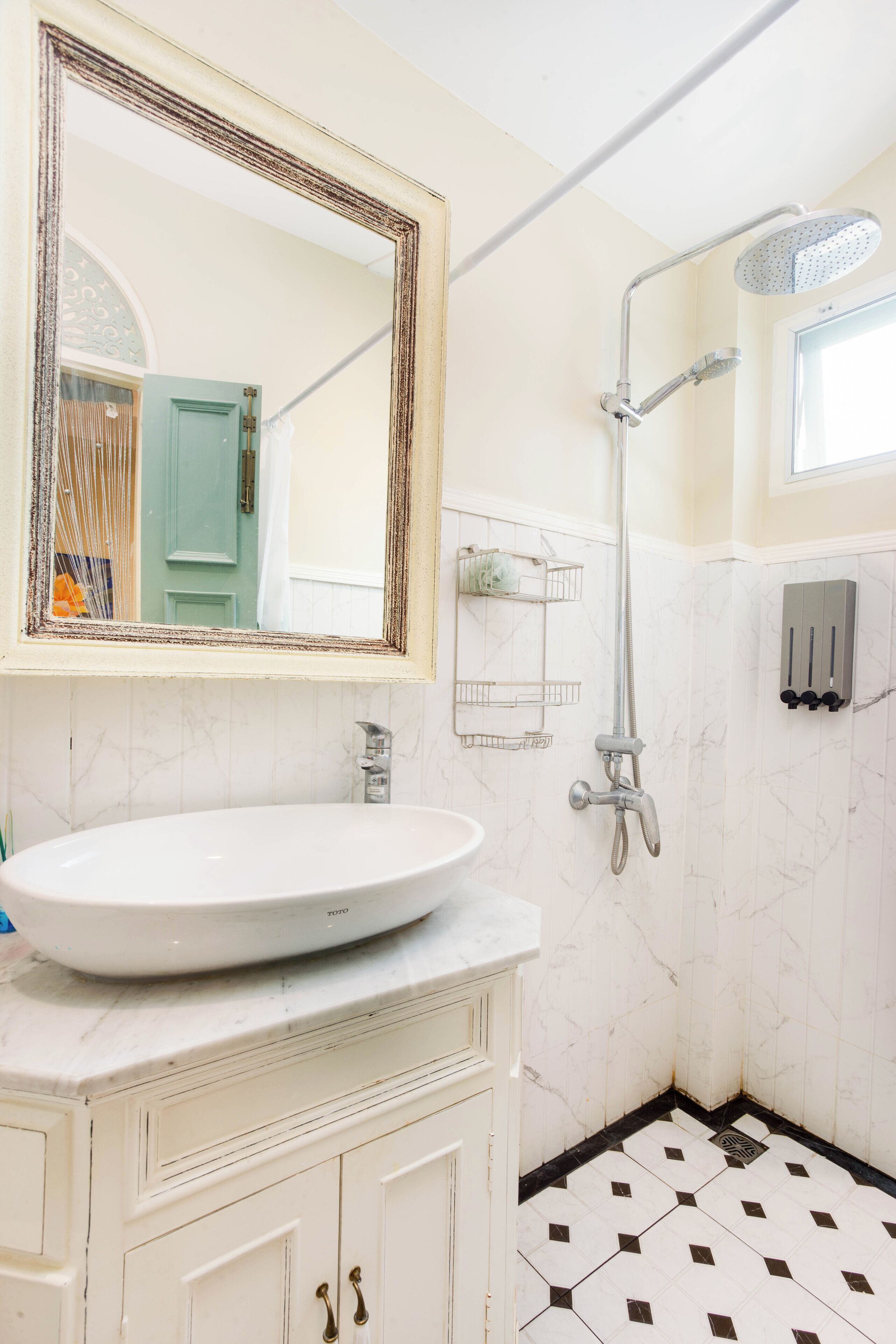 Een badkamer met een wit wastafelmeubel, een spiegel, een douche en een betegelde vloer.