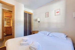Una camera d'albergo con un letto grande, una porta in legno, un comodino e una lampada a parete.