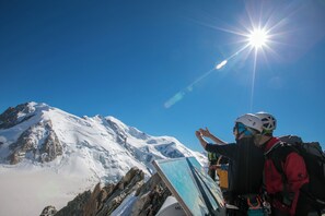 Une montagne enneigée, sous un ciel dégagé et un soleil éclatant.