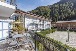 Hotel met terras, balkon en een berg op de achtergrond.