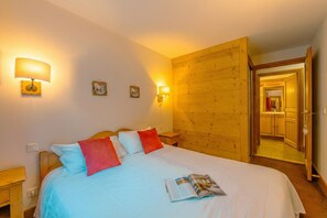 A bedroom with a bed, bedside lamps, and a wooden wall. - Vallorcine Loriaz 14 ski in / ski out, Vallorcine (Argentiere), France (Vallorcine (Argentiere))