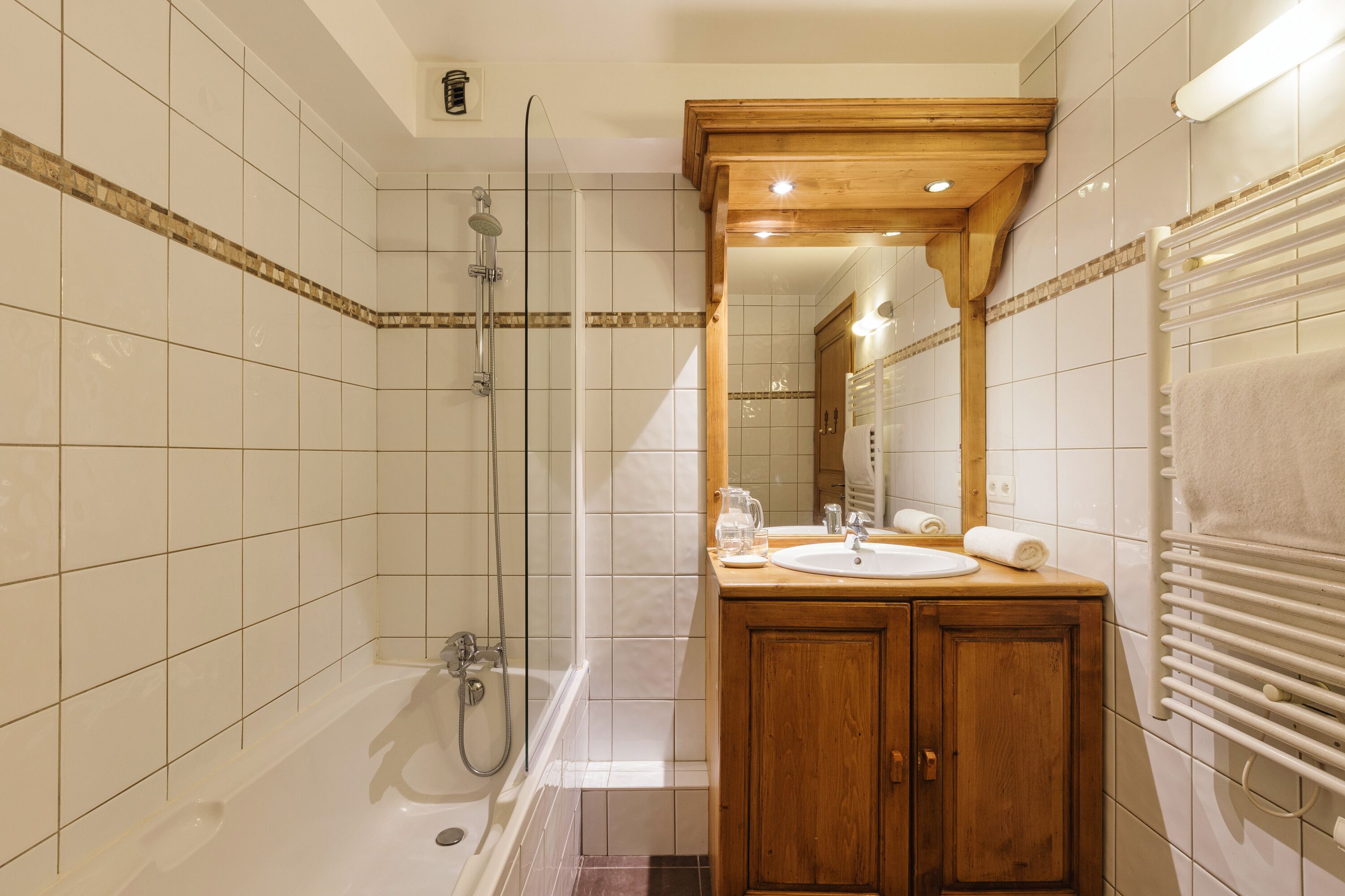 Un baño con bañera, ducha, tocador de madera y un espejo.