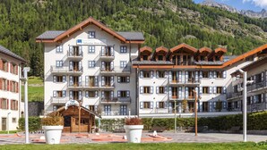 A multi-story hotel with balconies, a cafe, and a mountain backdrop. - V Buet 41: Beside Ski Lift; Pool, Sauna & Gym, Vallorcine (Argentiere), France (Vallorcine (Argentiere))