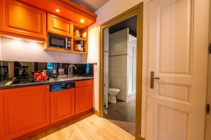 Une cuisine moderne avec des meubles de couleur orange, un four à micro-ondes et un lave-vaisselle.