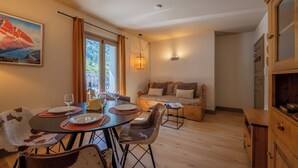A dining area with a table set for two, a sofa, and a wooden cabinet. - V Buet 41: Beside Ski Lift; Pool, Sauna & Gym, Vallorcine (Argentiere), France (Vallorcine (Argentiere))