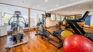 A gym with exercise equipment, large windows, and wooden flooring.